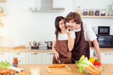 Couple cooking in kitchen Man taste food from girlfriend Happy couple at home enjoying life together relationship Girl giving food to Man to taste Wife cooking for her husband Male and female enjoying