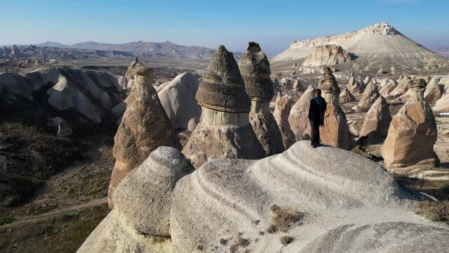 Aerial drone view of a person admiring the natural beauty of Pasabag Valley or Monks Valley and  Fairy Chimneys In Cappadocia, Turkey. Famous destination for hikers to explore the Rock Sites.