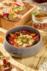 Salad with roasted potatoes, pulled beef, onions, and smoked sour cream in a rustic bowl