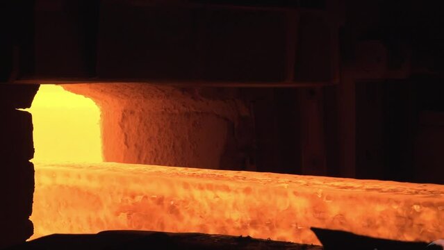 Metallurgy factory. Steel production in the workshop. Heavy industry. Red hot steel metal billets after molten steel casting. Hot metal sheet slides along the conveyor. Hot steel bars on the conveyor.
