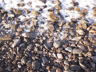 Rocky beach with Atlantic Ocean waves meeting with underwater sharp rocks. Blue sea with small waves with foam crashing on the beach, south of Tenerife, Canary Islands
