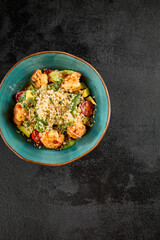 Top-down view of a vibrant shrimp and quinoa salad with avocado and tomatoes in a turquoise bowl