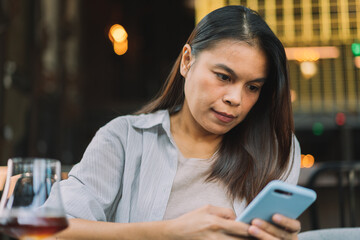 Portrait of beautiful asian woman with smartphone, relaxing in cafe, sitting and enjoying coffee while using mobile phone remote work online