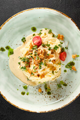 Velvety mashed potatoes crowned with succulent squid and golden caramelized onions, accented with fresh cherry tomatoes on an artisan turquoise plate