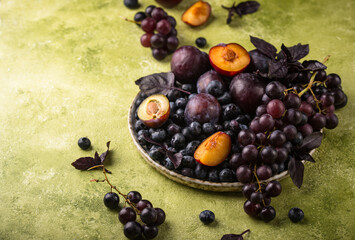 Assortment of purple fruit plum, grape, blueberry and basil