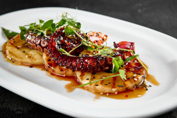 Grilled pineapple rings and tender octopus garnished with green herbs, served on a white elongated plate