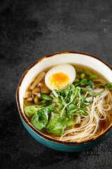 Traditional ramen with egg, greens, and mushrooms in a blue bowl
