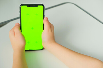 Close-up of children's hands holding smartphone with green screen