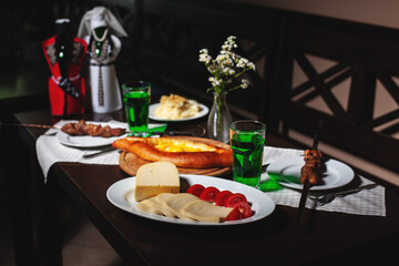 fresh Georgian meal with khachapuri, shashlik kebab with beef or lamb meat, tomato with cheese and green tarragon drink