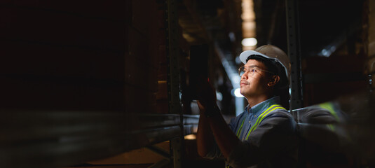 Asian engineer checks product details and supplies on shelves with stock in warehouse background....