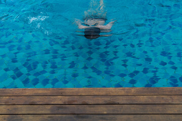 Obraz premium Man floating in swimming pool. Concept of a happy summer holiday travel.