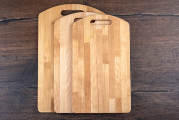Three empty wooden cutting boards on a wooden background.