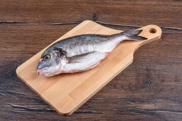 Fresh dorado fish on a wooden cutting board.