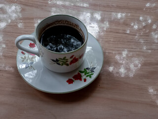 a cup of black coffee with a floral motif on the cup.