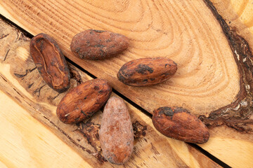 Several cocoa beans on a wooden table, macro, top view.