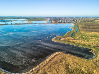 Aerial 4K footage of a frozen lake with people ice skating on a clear blue winter day in Sneek, the Netherlands 