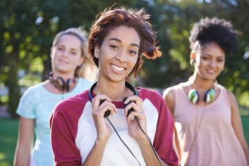 College, students and portrait in the park with headphones on campus to study together with...