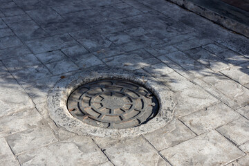 Manhole on the street next to a sidewalk, rusty manhole cap, grunge manhole cover, round edge, Rusty manhole cap, grunge manhole cover