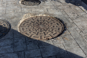 Manhole on the street next to a sidewalk, rusty manhole cap, grunge manhole cover, round edge, Rusty manhole cap, grunge manhole cover