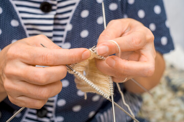Close-up of the hands of a young woman knitting with needles