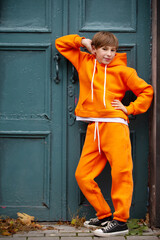 Fototapeta na wymiar A boy in an orange suit stands at a green door.