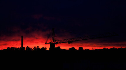 crane and pipe on the background of a fiery sunset sky