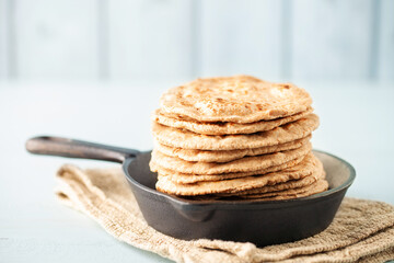 Homemade Indian Traditional Flatbread called Chapati on a white wooden background. Baked indian flatbread.