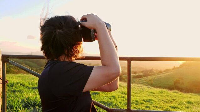 Man with long hair taking pictures of a sunset