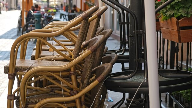 Outdoor Chairs and Tables Stacked and Secured for Night with Metal Steel Cable and Padlock In front of Boulveard Pub Cafe Coffee Shop Before Opening Hours