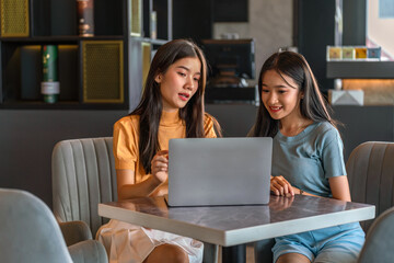 Weekend Out-of-Office Collaboration. Two young Asian woman break away from the office, opting for a cozy café to discuss work. 