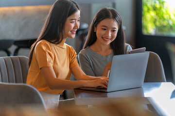 Weekend Out-of-Office Collaboration. Two young Asian woman break away from the office, opting for a cozy café to discuss work. 