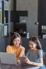 Weekend Out-of-Office Collaboration. Two young Asian woman break away from the office, opting for a cozy café to discuss work. 