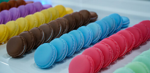 Rows of the colorful tasty macarons on white tray background, dessert concept. Close up.