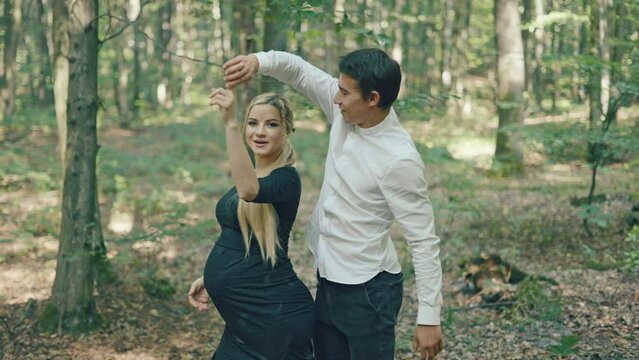 Young pregnant woman and her husband having fun in park. Happy family outdoors. Expecting for firstborn	