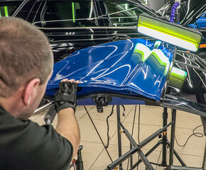 Removing dents on the car. PDR technology. Car body repair without painting. A specialist repairs a...