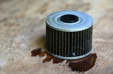 used oil car filter on wood table .  used oil filter of a motorcycle engine . 