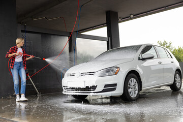 Woman in red shirt cleaning the car at car wash