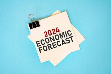 Text 2024 ECONOMIC FORECAST, on sticky notes with copy space and paper clip isolated on red background. Finance and economics concept.
