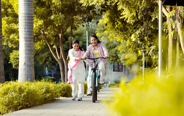 Mother helping daughter in cycling in Outdoor Garden, Mother and daughter Bonding ,
