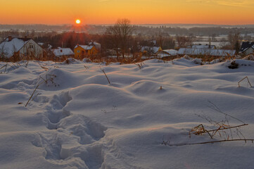 Zachód słońca zimą, krajobraz, ślady stóp na śniegu.
