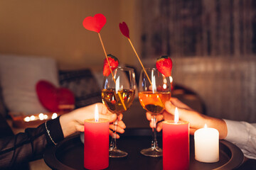 Valentines Day couple in love clinking glasses drinks wine with strawberries having romantic dinner...