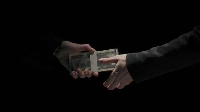 Portrait of business people in suits isolated on black background. Business women partners make deal handshake after receiving money bribe.