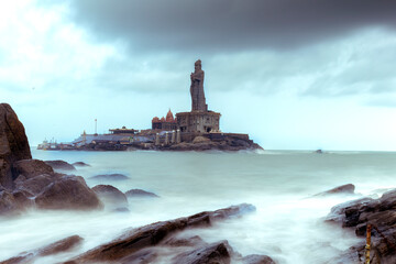 lighthouse on the coast of the sea at kanyakumari place in India, slow shutter milky water at Thiruvalluvar Statue in a cloudy day