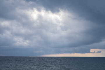Dark dramatic view of clouds and stormy weather over the Black Sea, the sun's rays pass through...