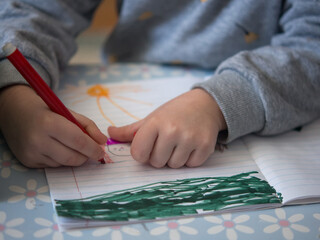 Children's hands draw with a felt-tip pen. girl sits at the table and draws