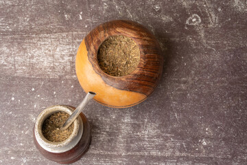 Yerba Mate tea with a small wooden mate next to a gourd filled with yerba mate, on a light gray...