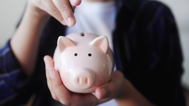 Hand putting coin in pig moneybox for saving money. Financial and invest concept