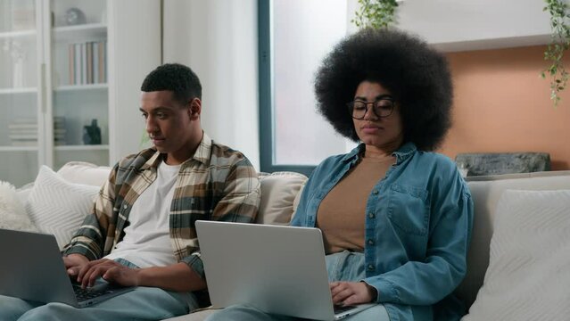 Sad lonely African American woman wife girlfriend need attention looking on husband man internet addict guy playing video game addicted online exhale problem couple with two computers laptops at home