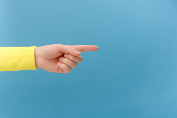 Close up of female hand pointing on copy space for design, isolated on blue color background wall in studio. Advertisement place for text image promotional content Advertising area workspace mock up