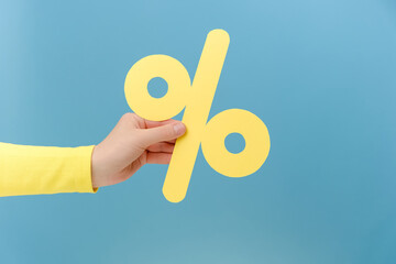 Close up of woman hand holding paper yellow percent mark, presenting big discounts, posing isolated...